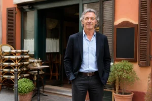 Alain Pic devant son ancien restaurant français fermé, illustrant son parcours après sa carrière professionnelle